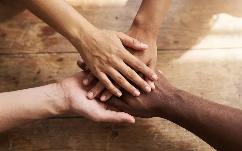 Many hands of different skin tones joined together in a circle